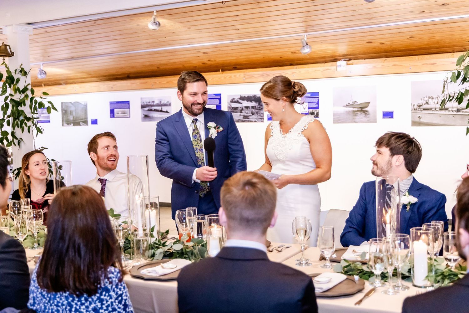 Bride and groom share a toast with guests at an elegant wedding reception dinner with floral table settings.