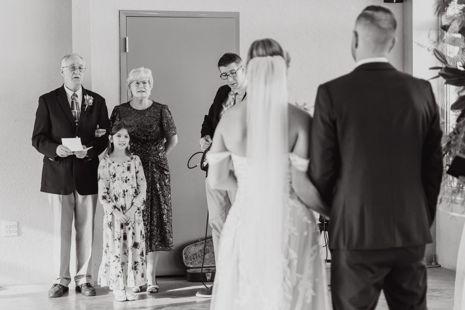 Black and white photo of wedding ceremony with guests watching the proceedings.