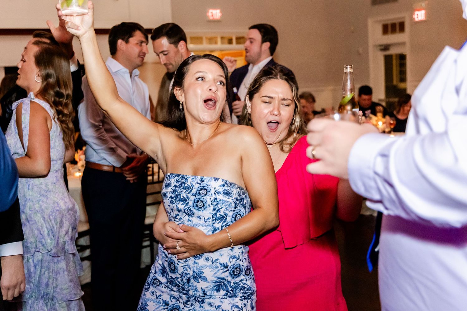 Energetic dance party scene with guests in colorful dresses at wedding reception.