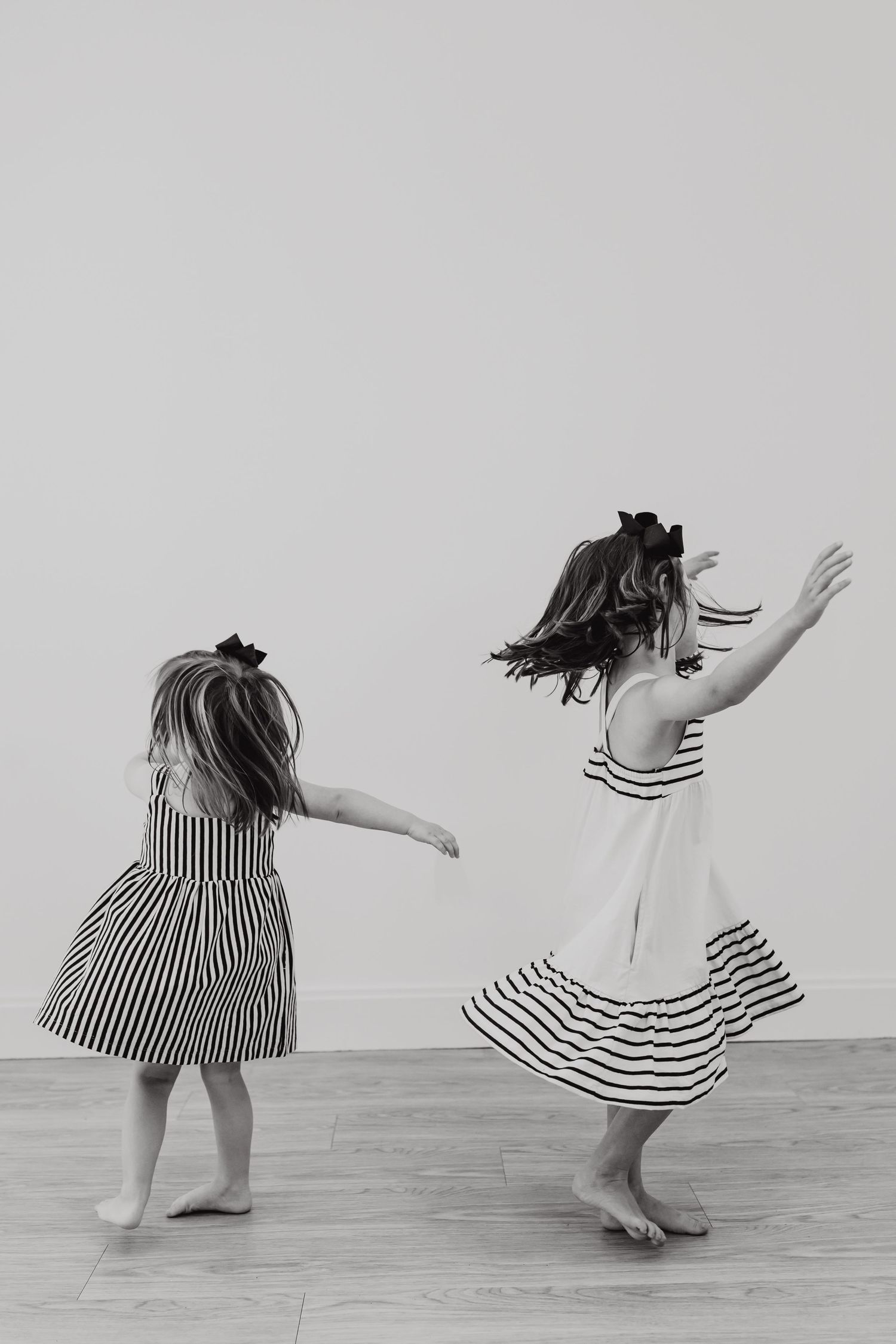 Artistic black and white sequence showing dancing movements in striped dresses on a wooden floor.