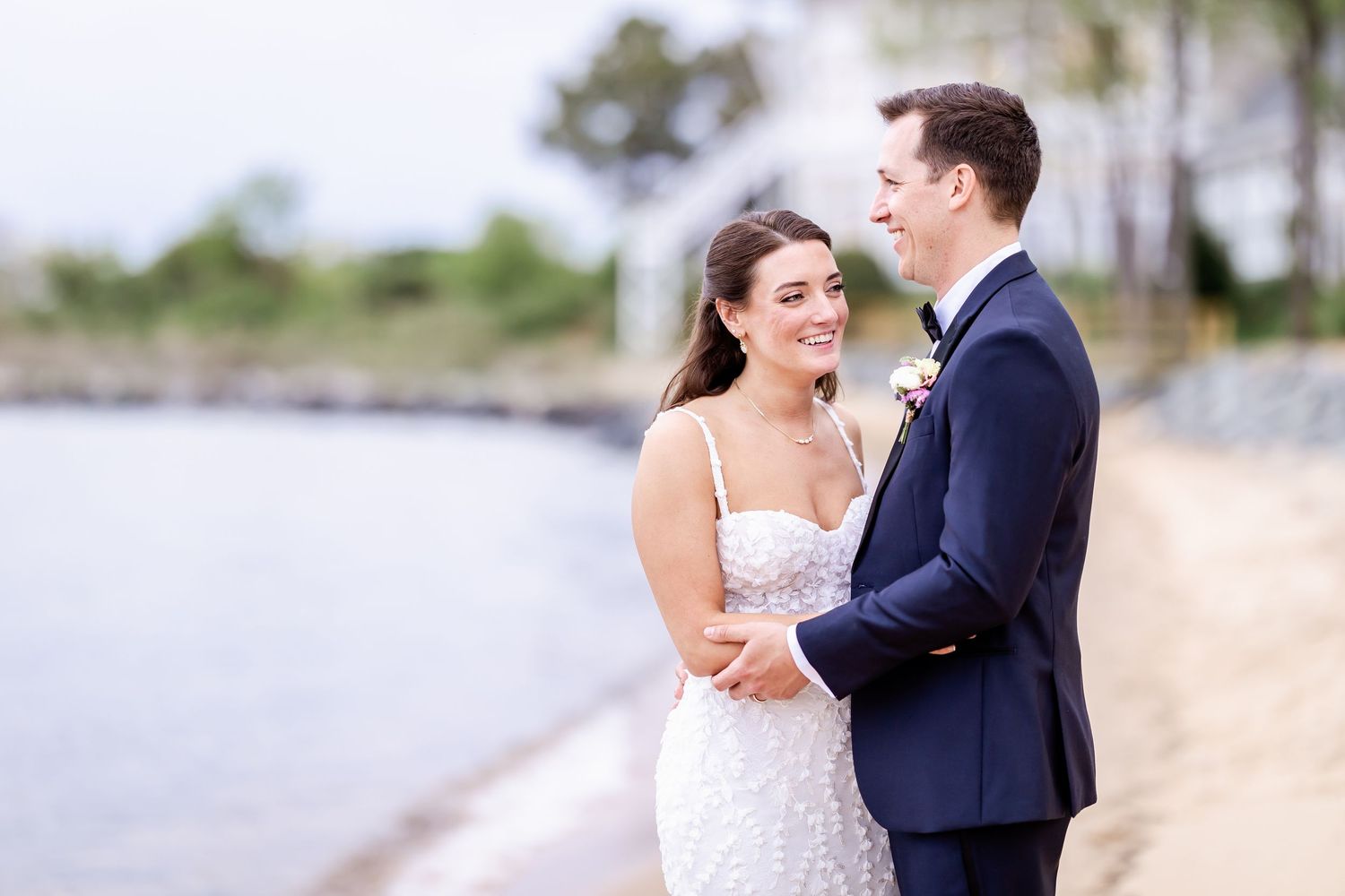 Couple shares a romantic moment together on a sunny beach with palm trees in the background.