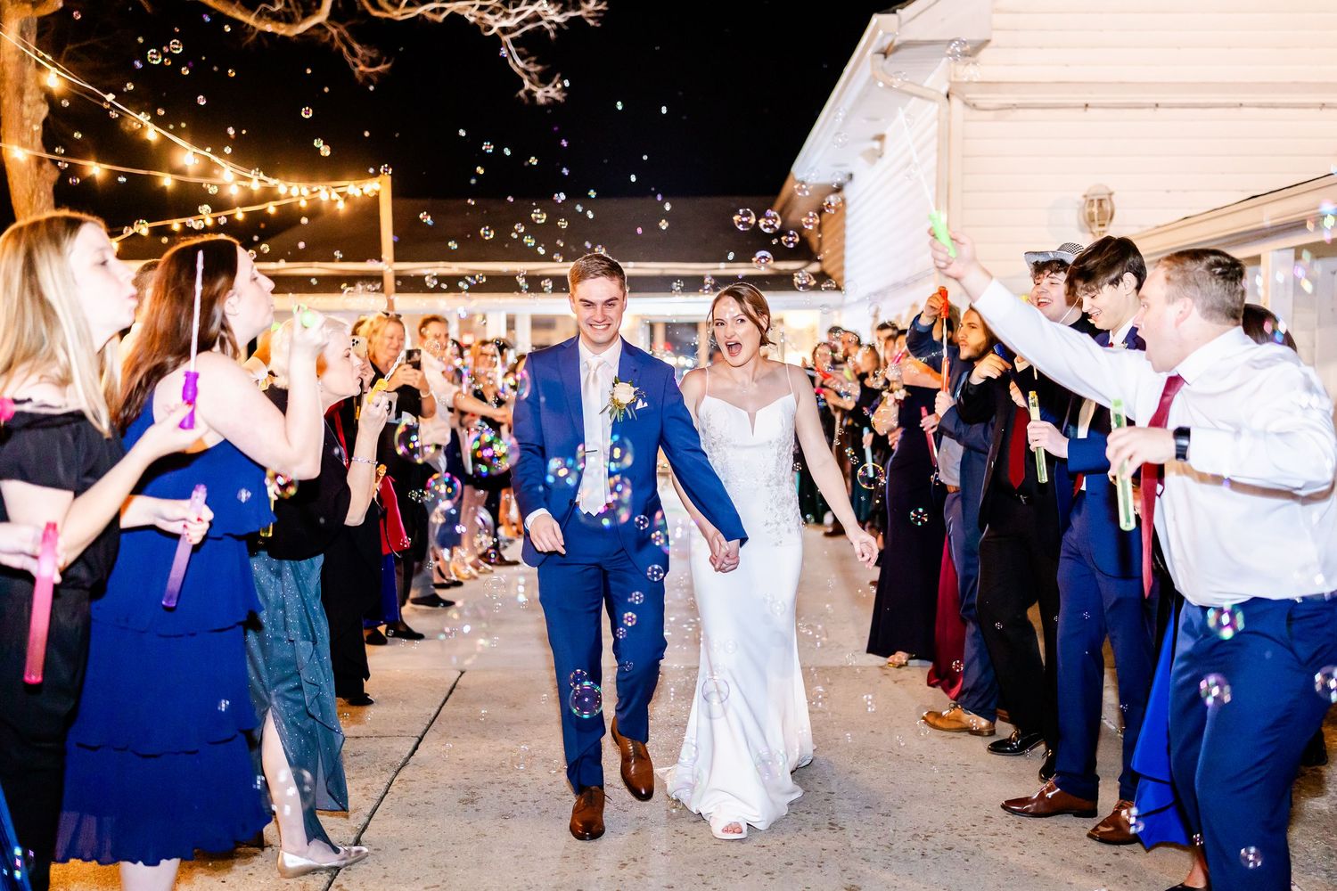 Wedding guests form a sparkler exit line outside venue at night for the newlyweds.