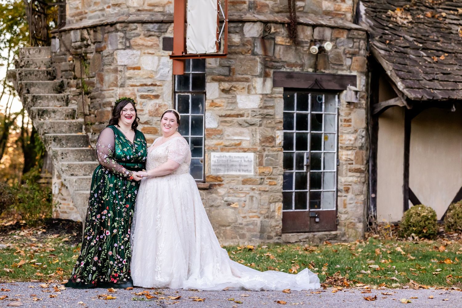 Wedding party members in contrasting white and green dresses posing outside stone building.