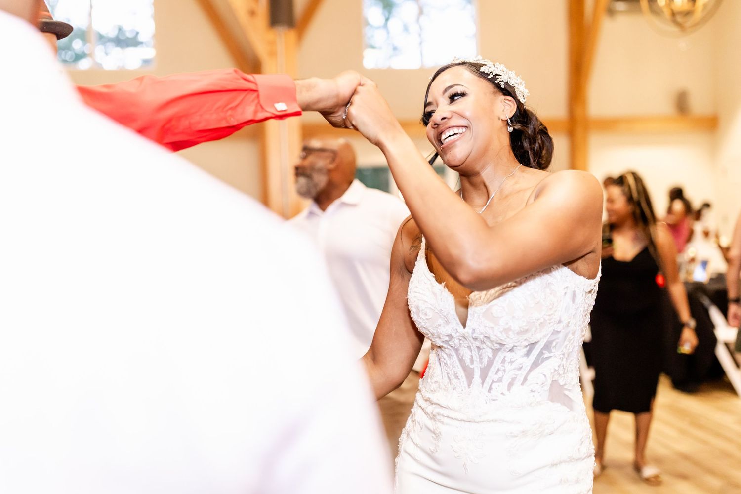 A bride in a white dress singing energetically at her wedding reception.