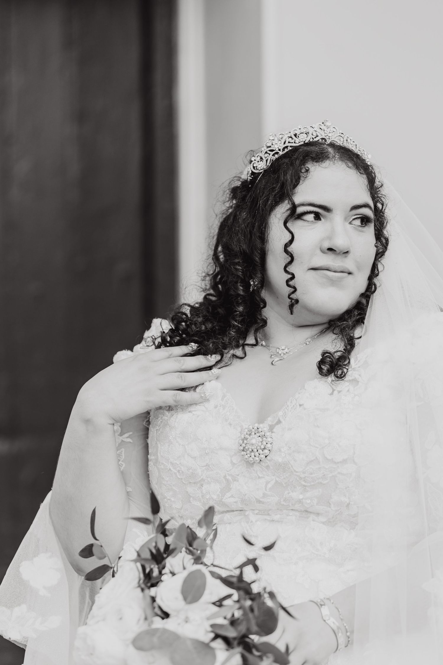 Black and white bridal portrait highlighting elegant wedding attire and natural curls with flowing veil.