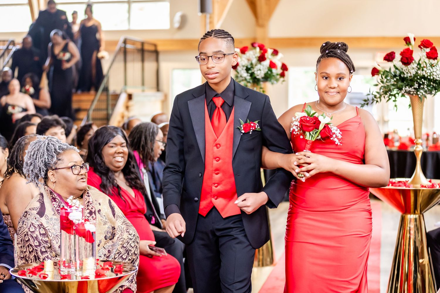 Wedding party members in formal attire with red accents during ceremony.