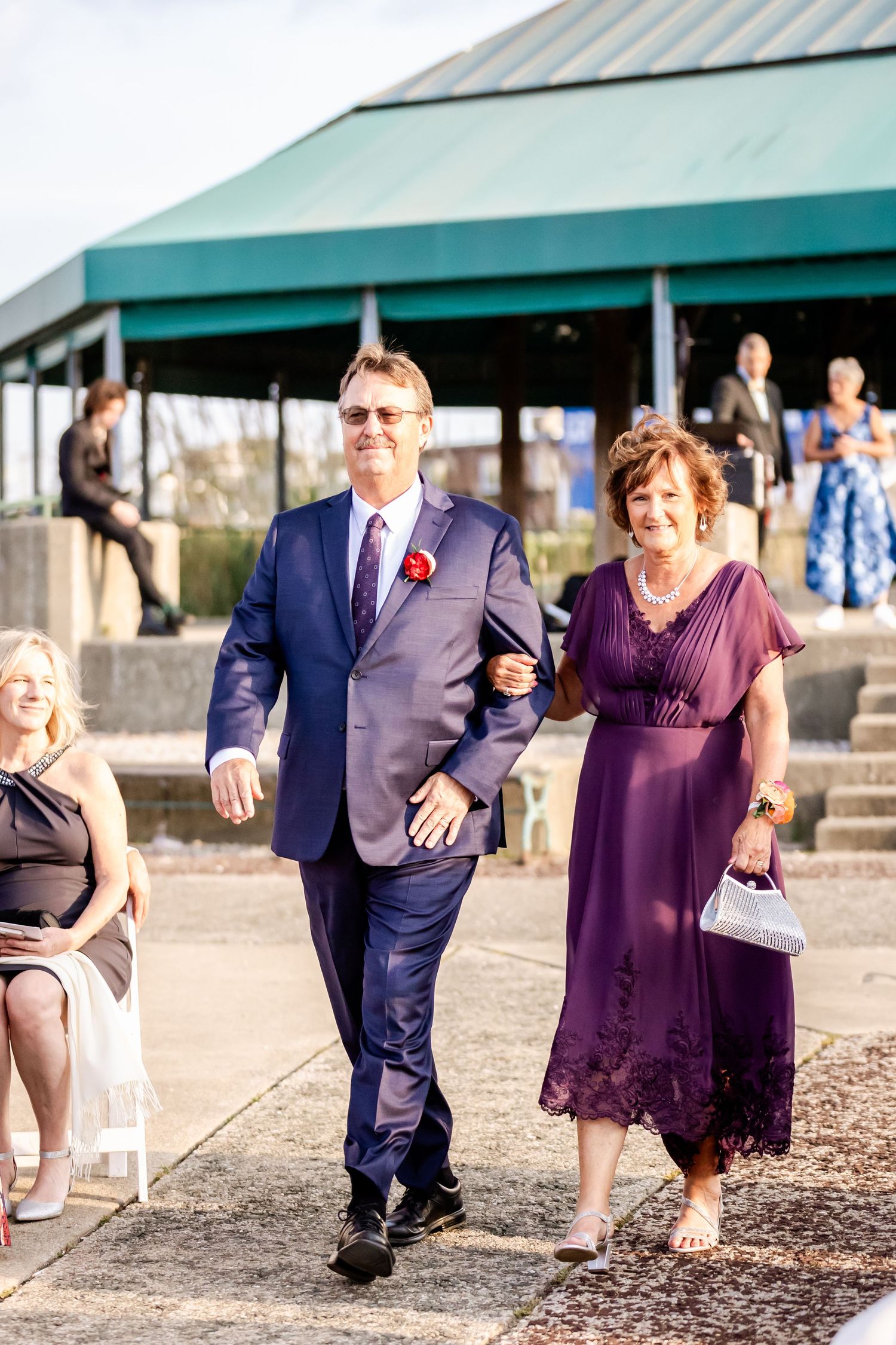 Formal wedding attendees walking down outdoor stone steps at daytime event.
