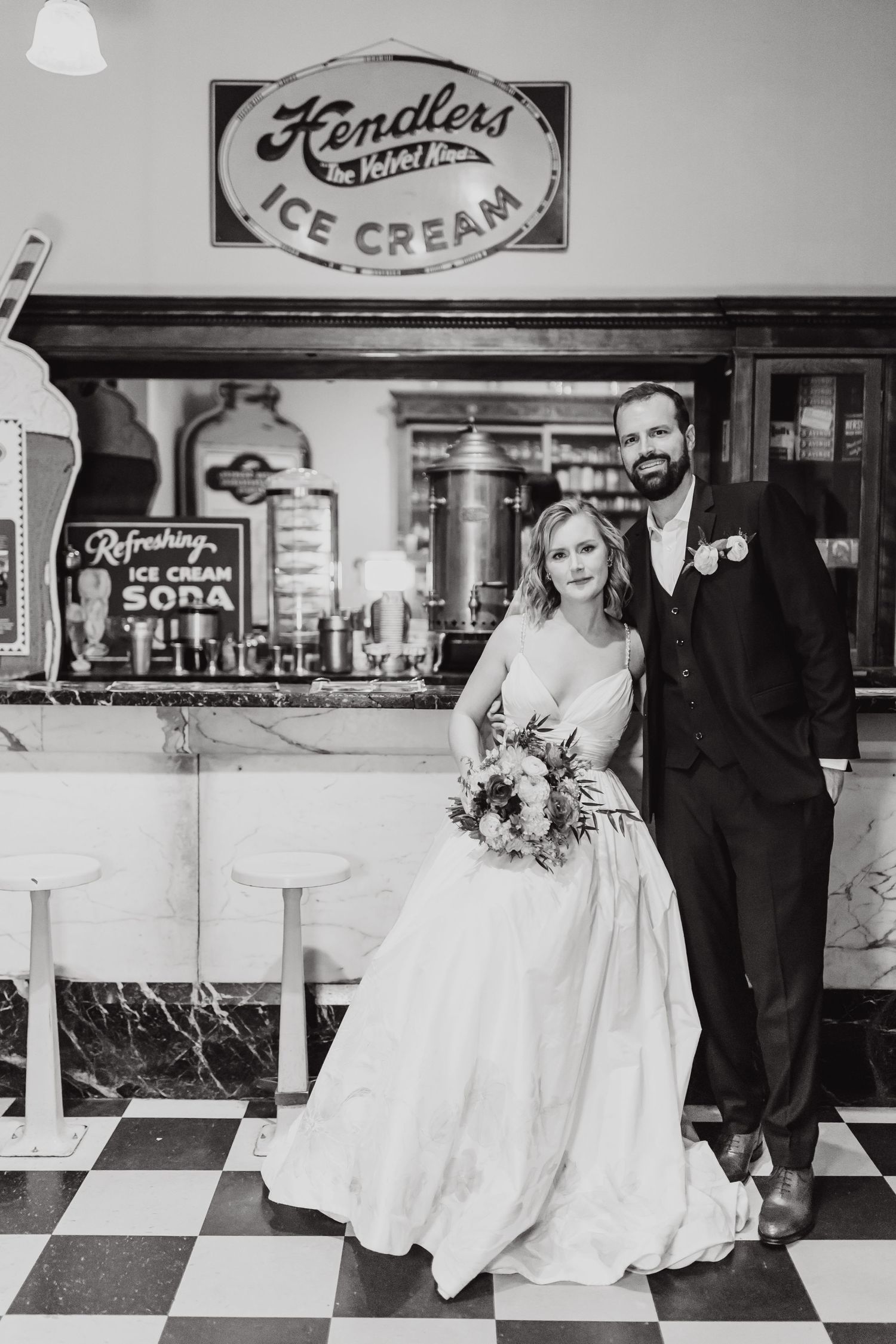 Black and white wedding portrait at retro Fendlers Ice Cream shop with vintage signage.