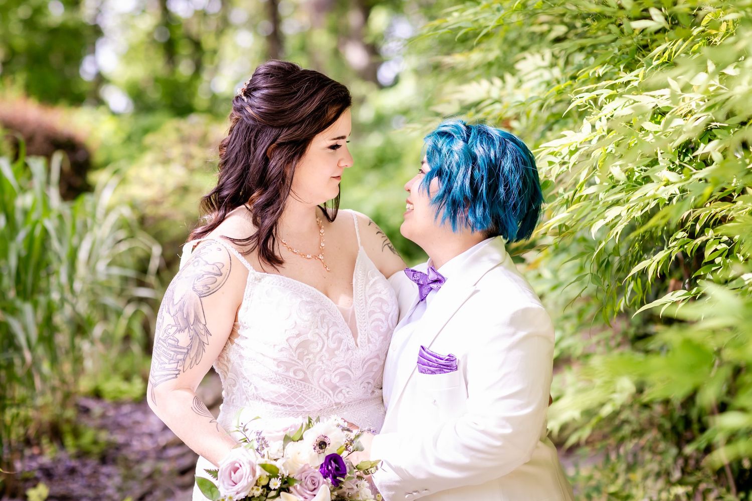 A romantic garden portrait of a couple surrounded by green foliage wearing wedding attire.