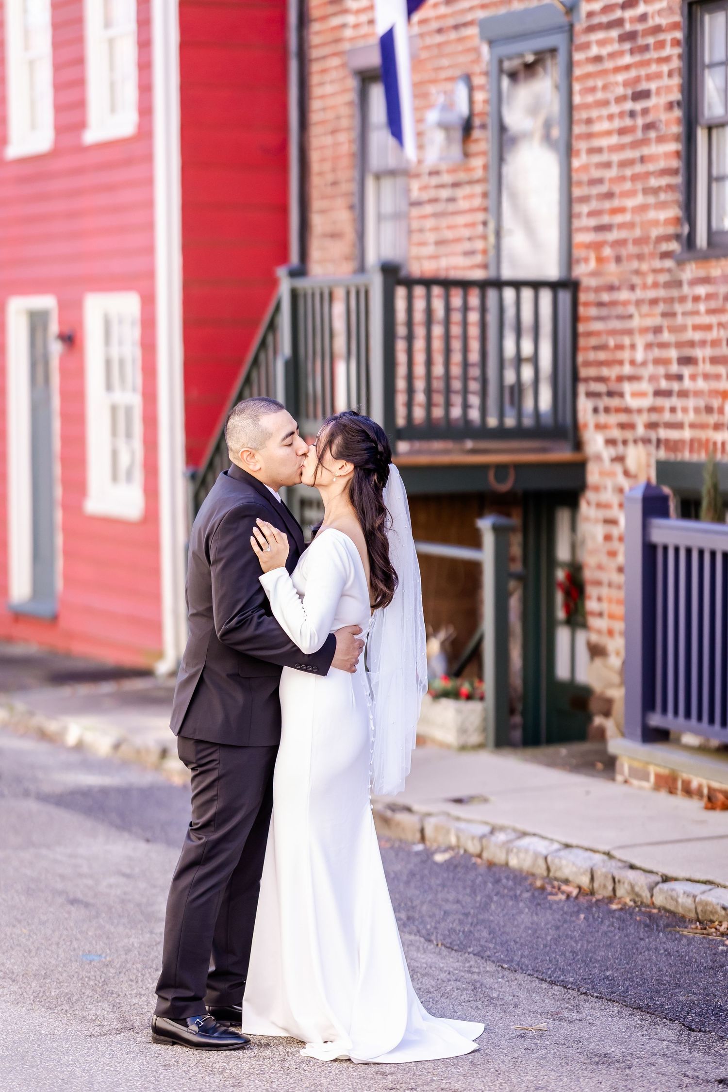 A touching wedding moment captured on a historic street with red and brick buildings in the background.