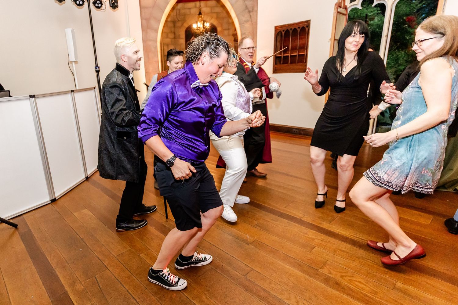 Wedding guests dancing and enjoying themselves on wooden dance floor during reception.