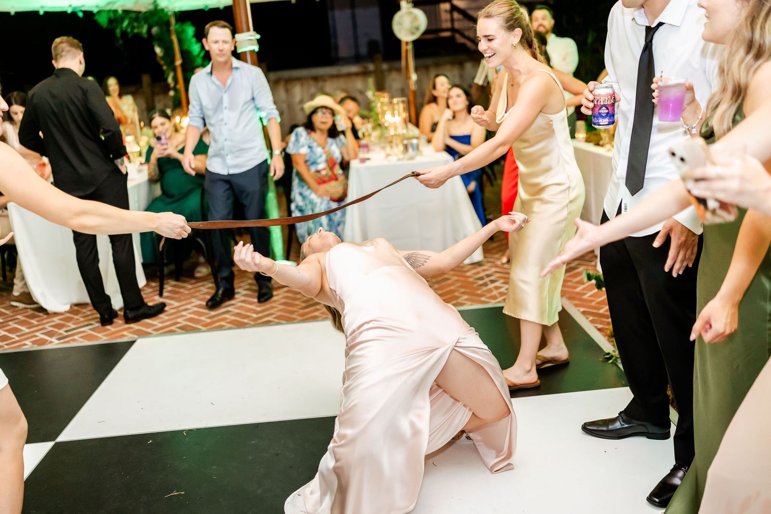 Wedding guests dancing and celebrating on outdoor patio during evening reception.