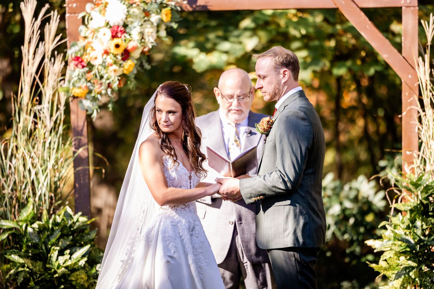 Romantic outdoor wedding ceremony setup with wooden arch and floral decorations.