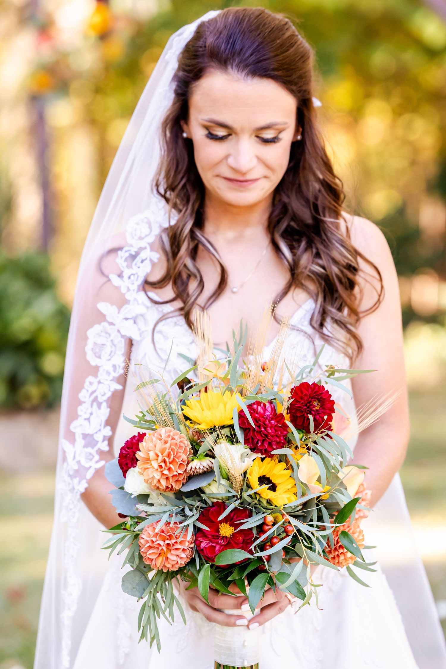 Vibrant autumn bridal bouquet featuring sunflowers, red roses, and orange dahlias with eucalyptus.