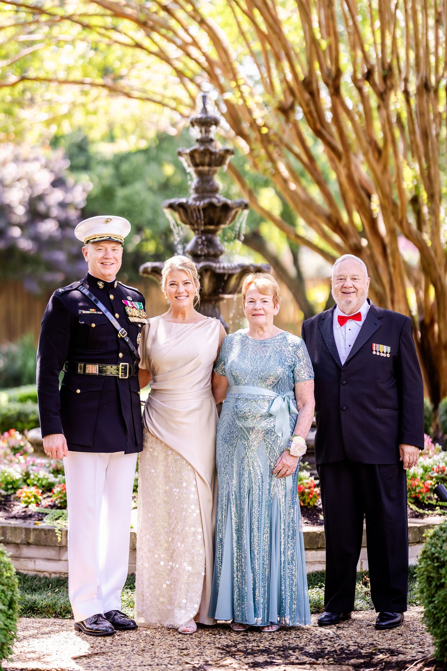 Group photo of wedding guests in formal attire posing together in a garden setting.