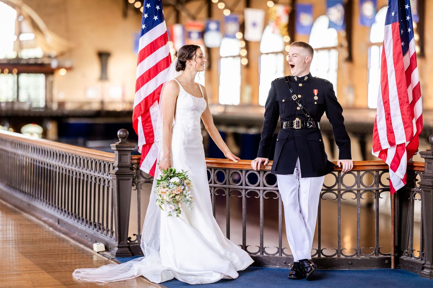 Wedding party poses with American flags in front of classic architecture.