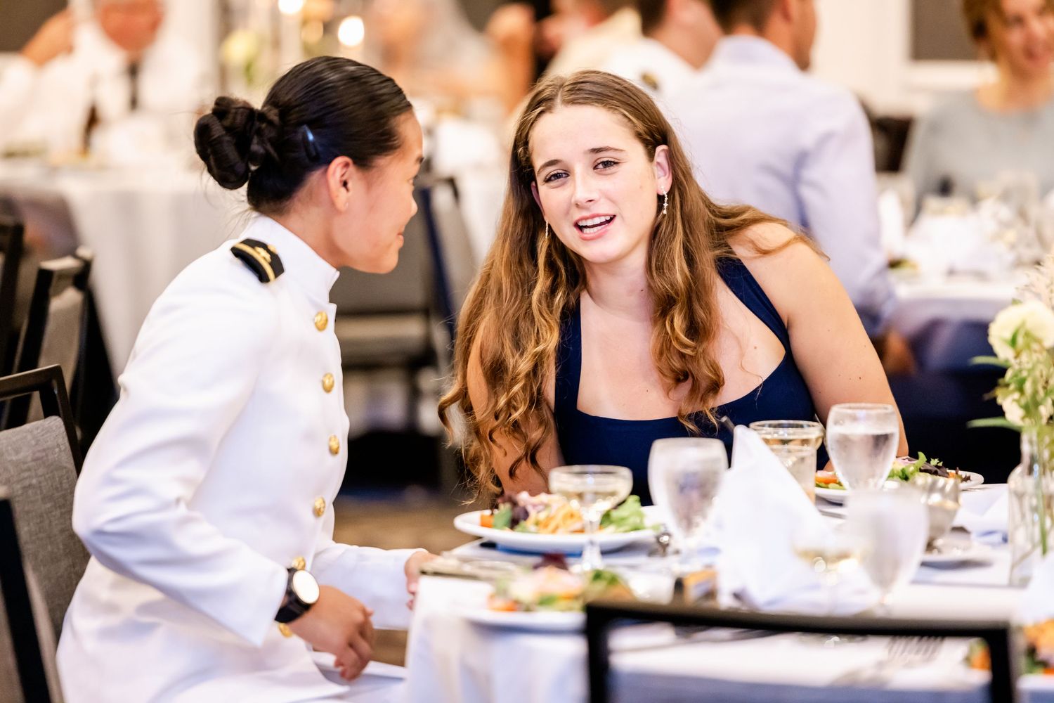 Wedding guests enjoying dinner and conversation at elegantly decorated reception tables.