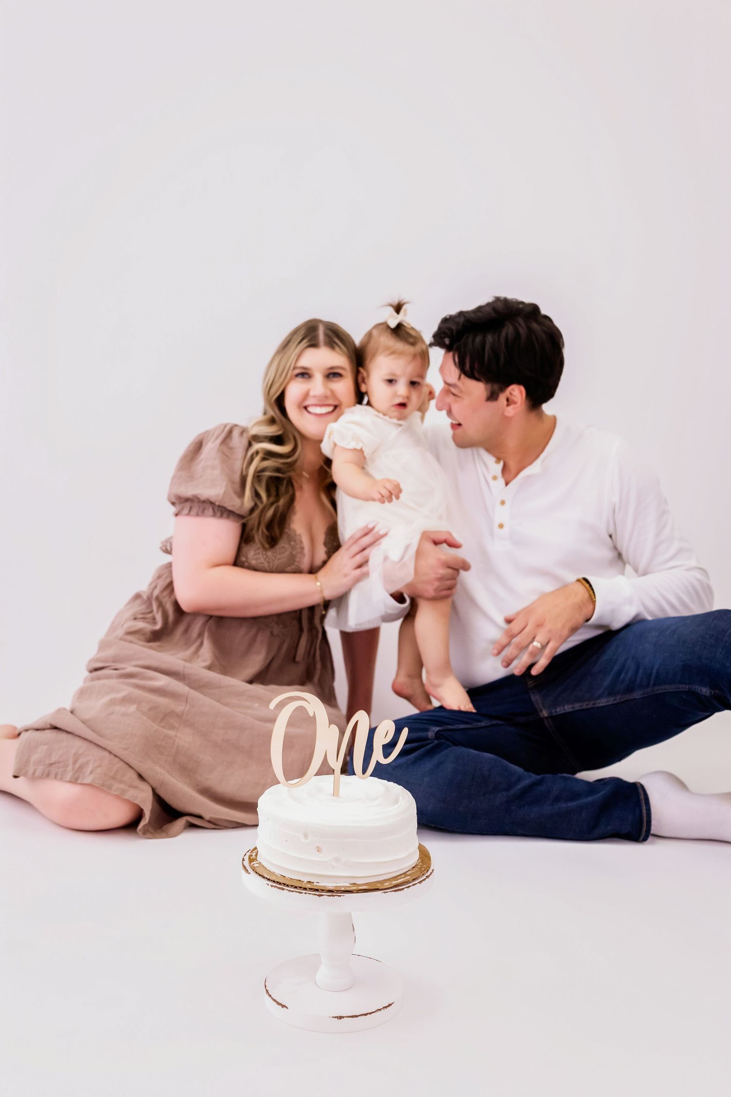 A family celebrates with a white cake during a casual studio photo session.