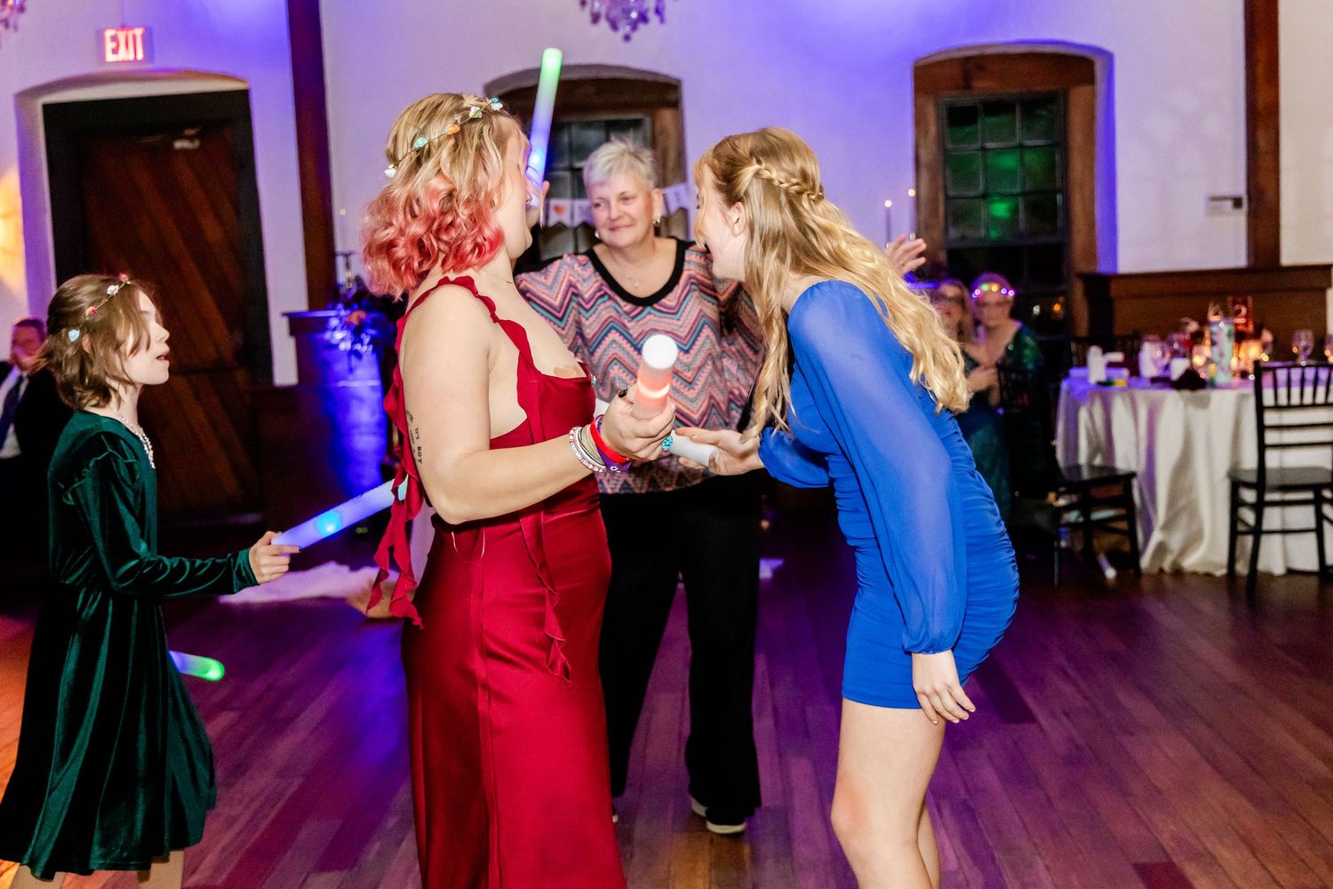 Wedding reception dance floor filled with guests celebrating under purple and blue lighting in an elegant ballroom.