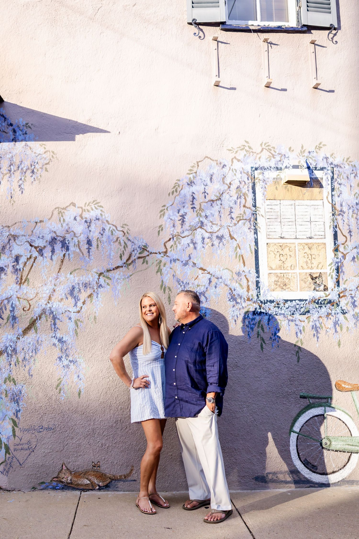 A series of four progressive photos showing a couple posing playfully against a blue and white painted wall.