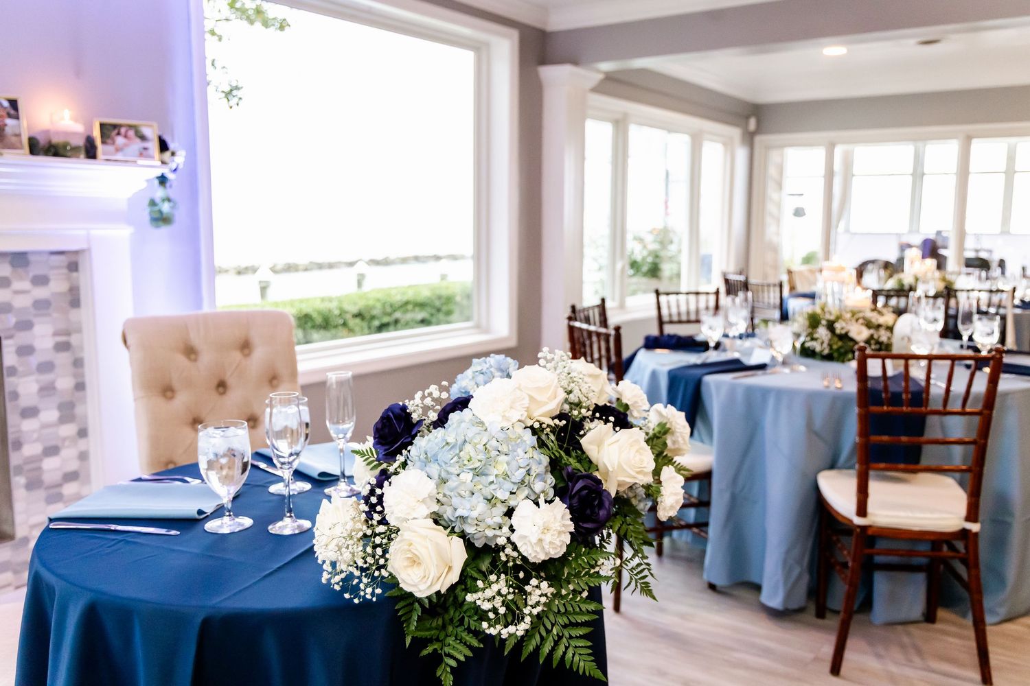 A bright reception venue decorated in shades of blue with elegant table settings and chairs.