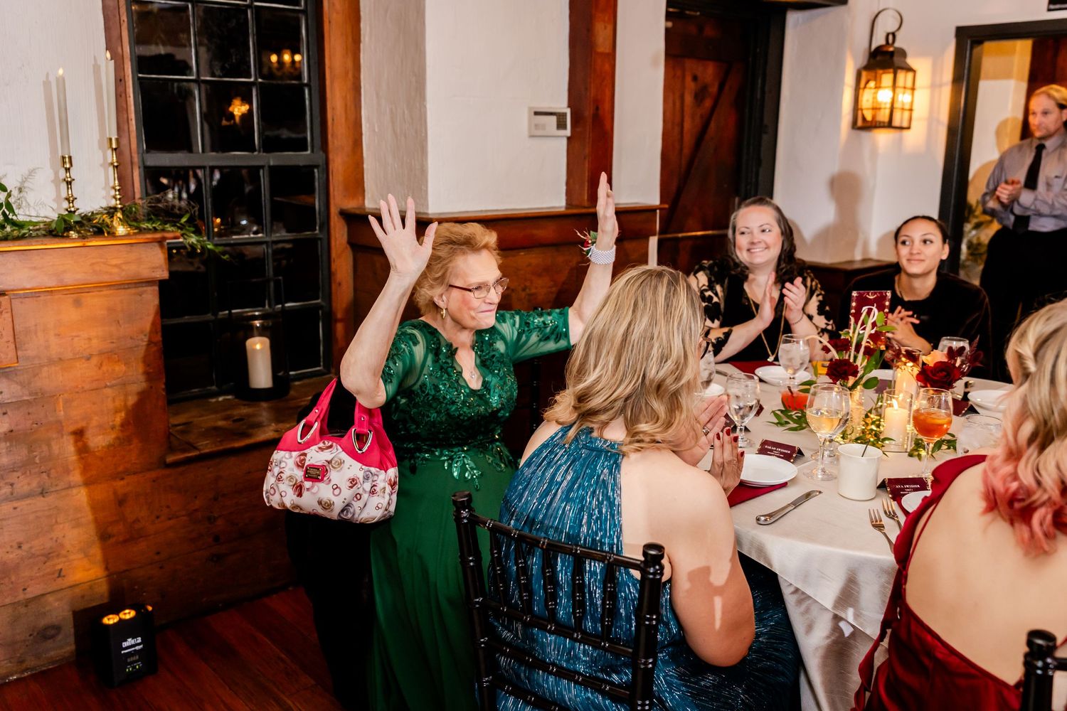 Guests celebrating and raising their hands at a dimly lit reception venue.