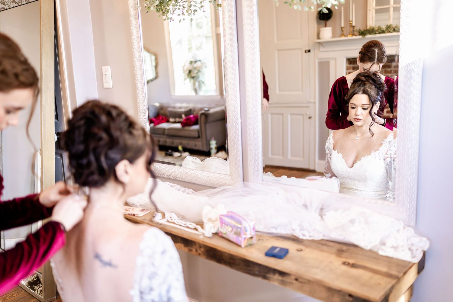Wedding party getting ready at vintage-style vanity mirrors in bright indoor setting.