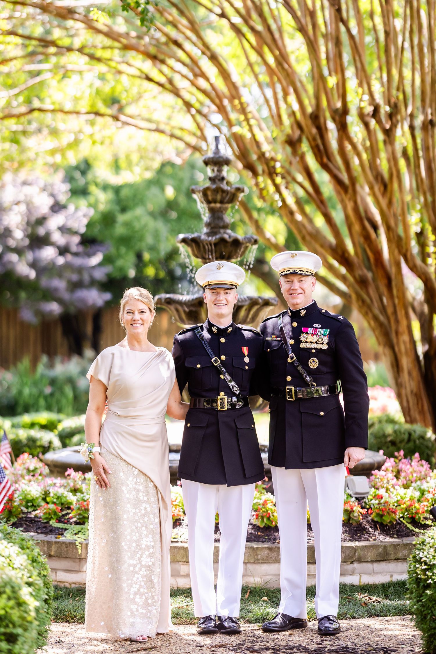 Military wedding portrait in a garden setting with formal uniforms and a decorative fountain.