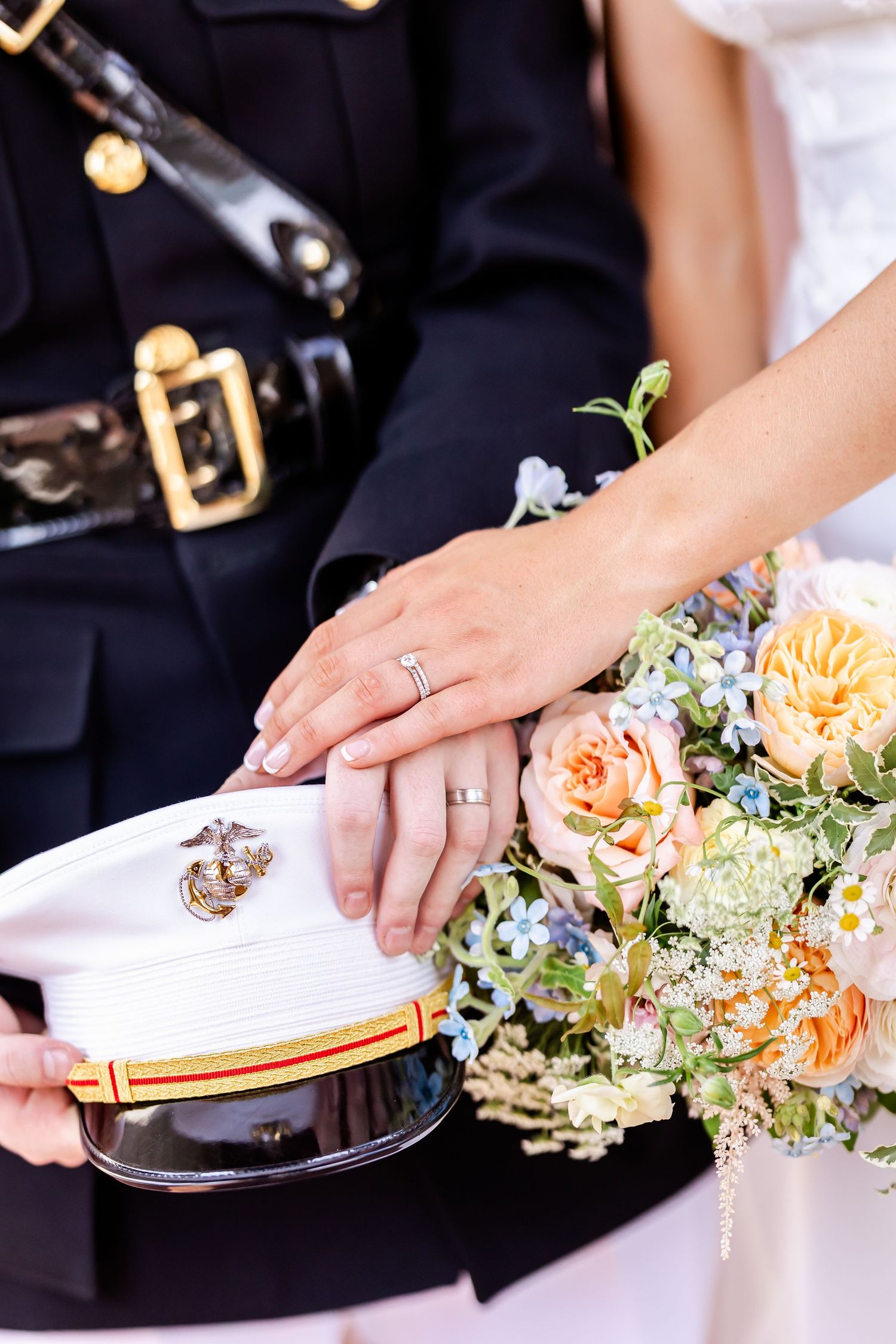 Close-up of wedding rings and peach floral arrangements on table settings.