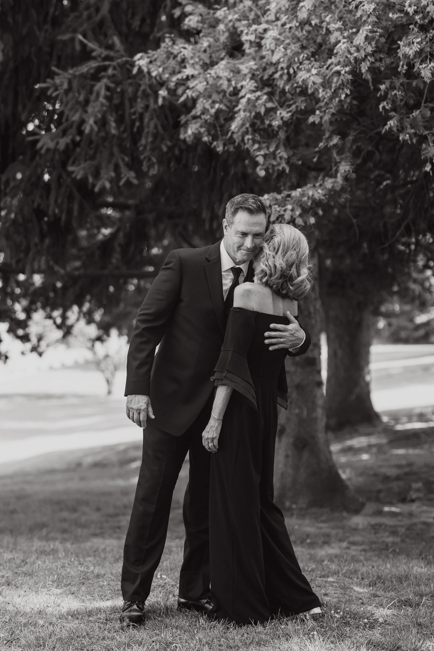 A romantic black and white portrait of a couple embracing outdoors.
