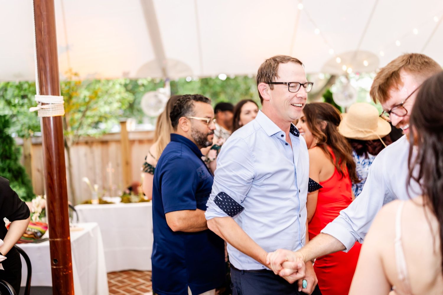 Guests dancing and socializing at an outdoor tented wedding reception.