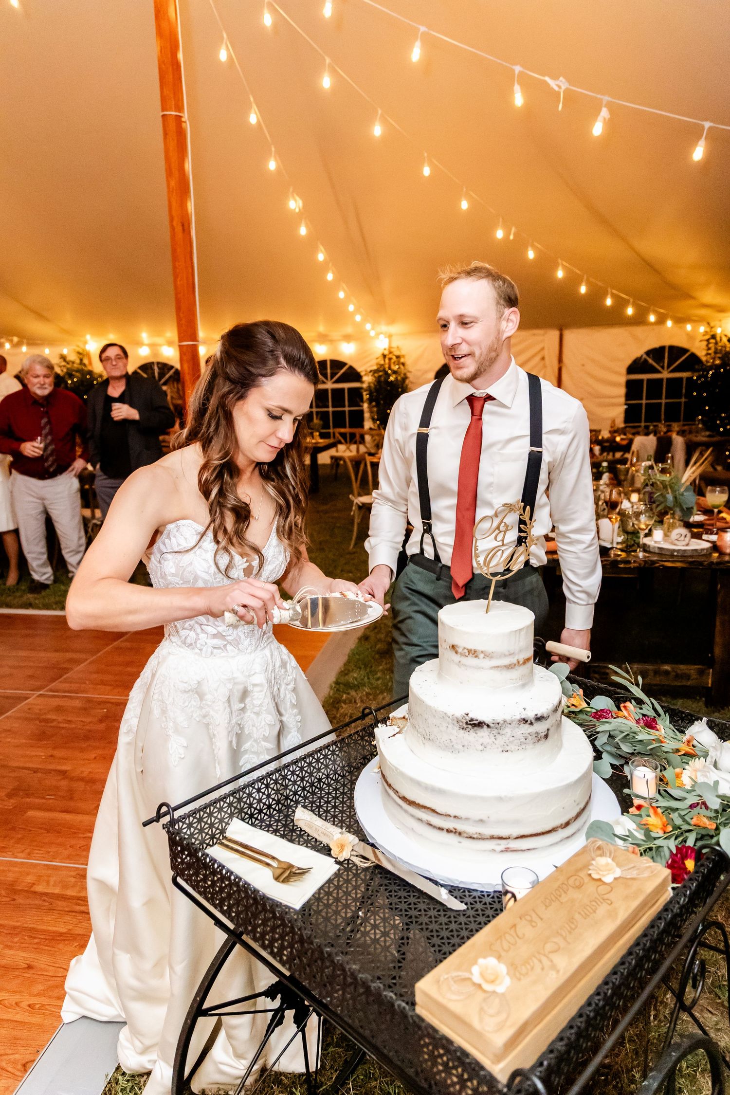 Newlyweds sharing their wedding cake cutting moment at reception under warm string lights.