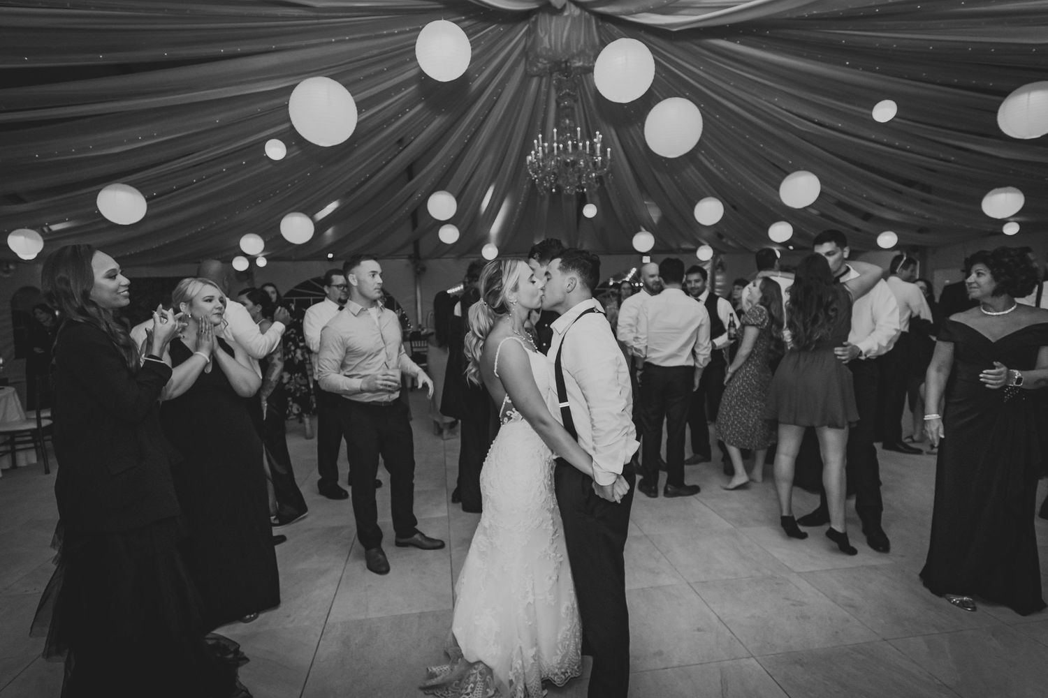 Black and white photo of an elegant dance floor celebration with dynamic lighting and reception guests.