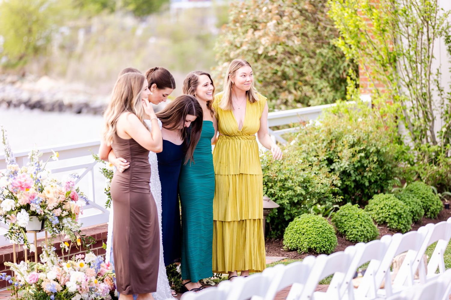 Wedding guests in colorful formal attire pose together in a garden setting.