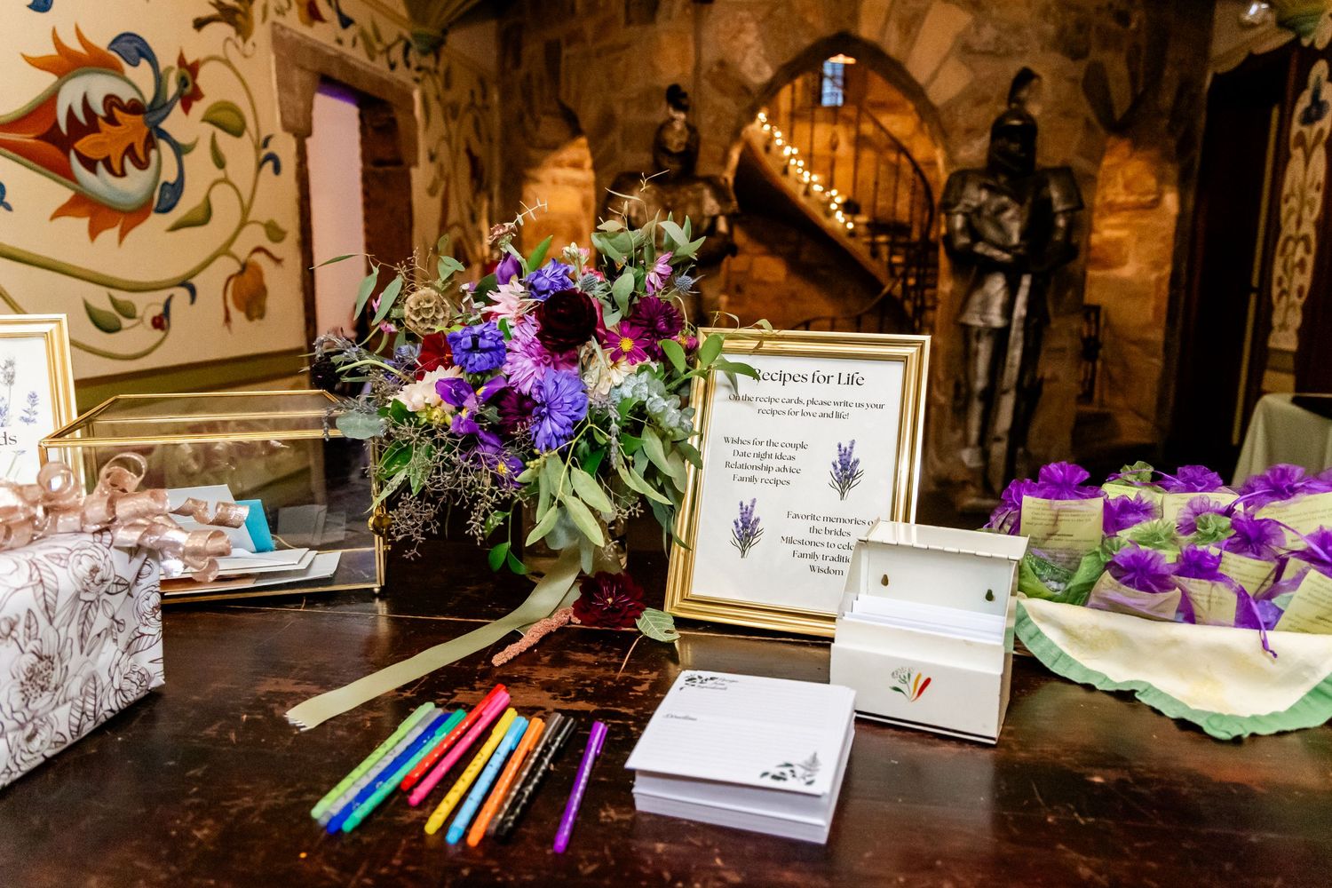 Wedding guest book table with purple flowers and colored pencils for signatures.