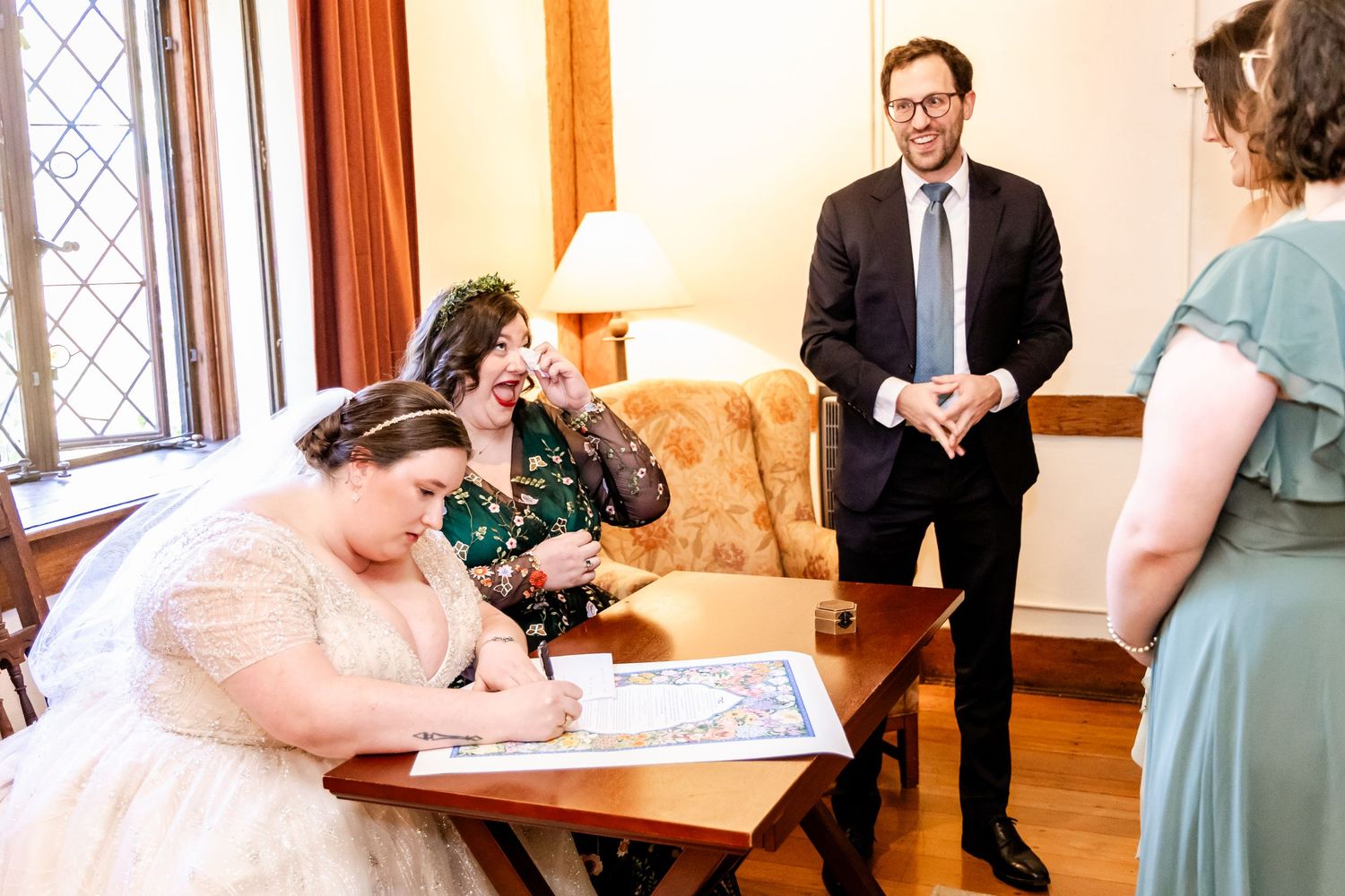 A wedding ceremony signing moment in an elegant indoor setting with witnesses present.