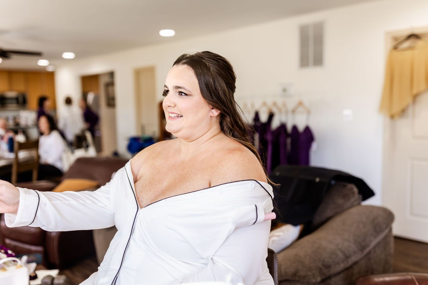 Getting ready scene with person in white robe smiling during wedding preparation.