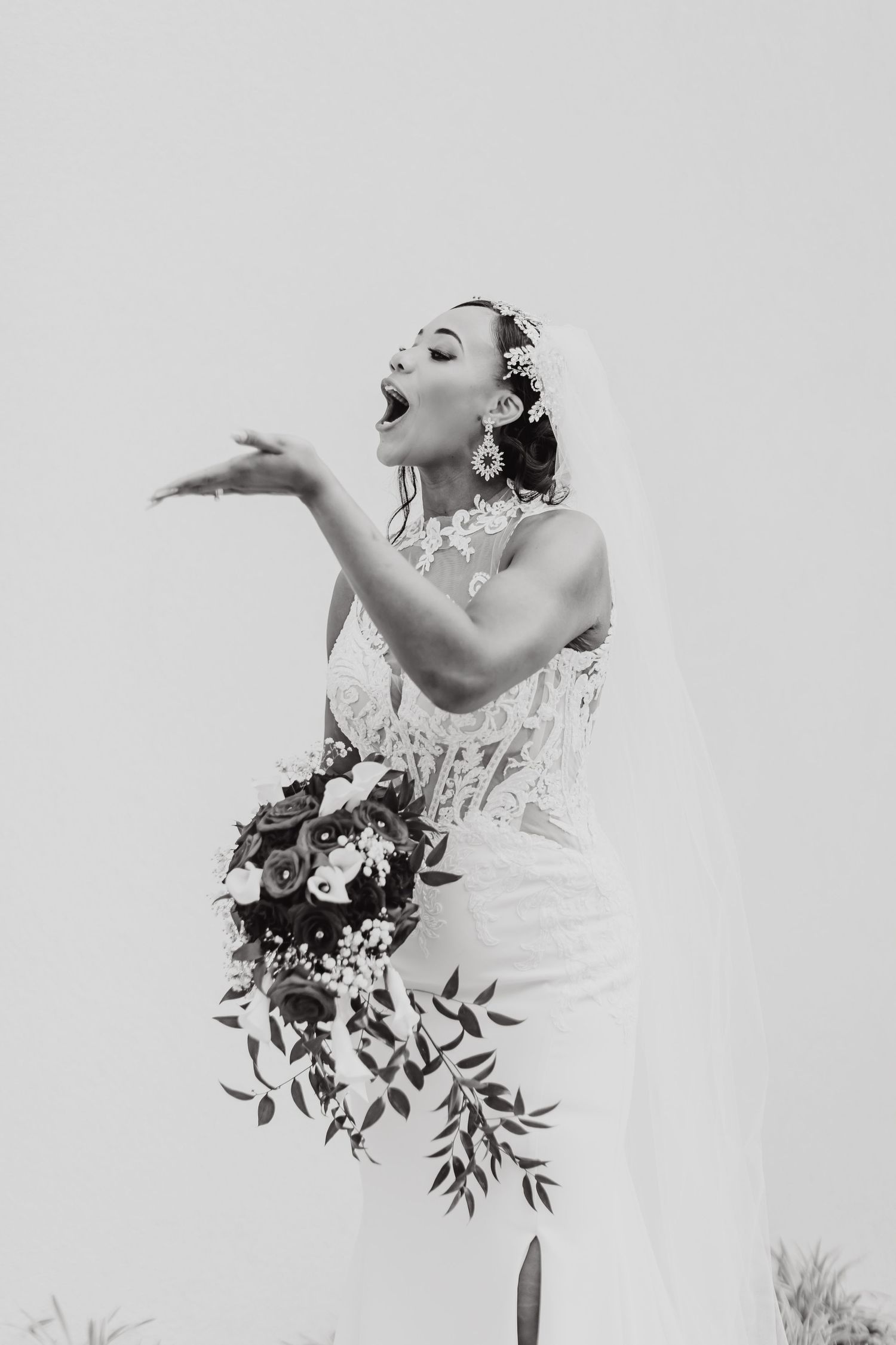 Black and white portrait of a joyful bride blowing a playful kiss.
