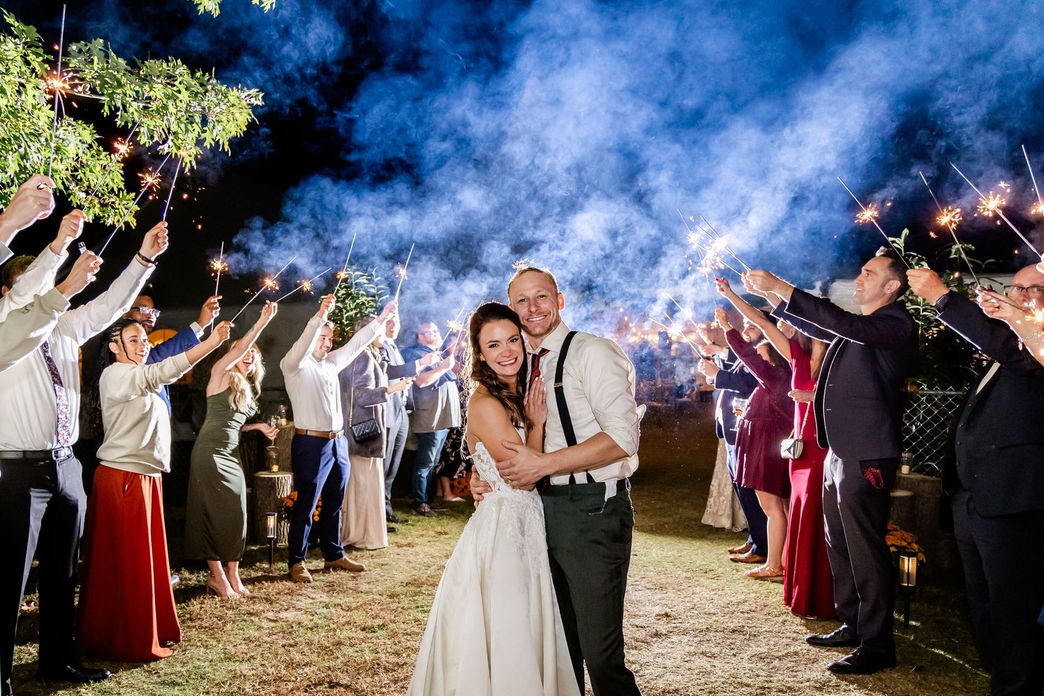 A couple dances at their nighttime wedding reception while guests hold sparklers creating a magical light tunnel effect.