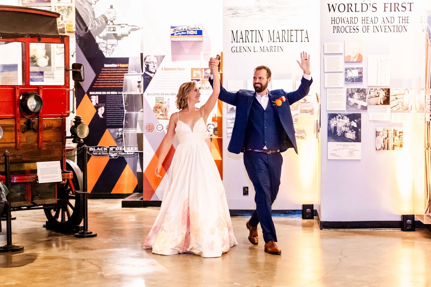 A couple dancing joyfully in front of historic displays in a museum setting.