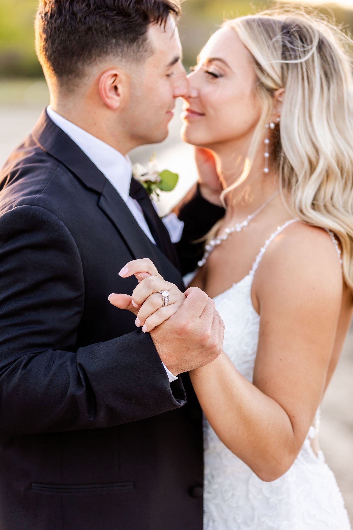 A romantic wedding photograph showing a couple dancing closely together, with the bride wearing a white lace dress.