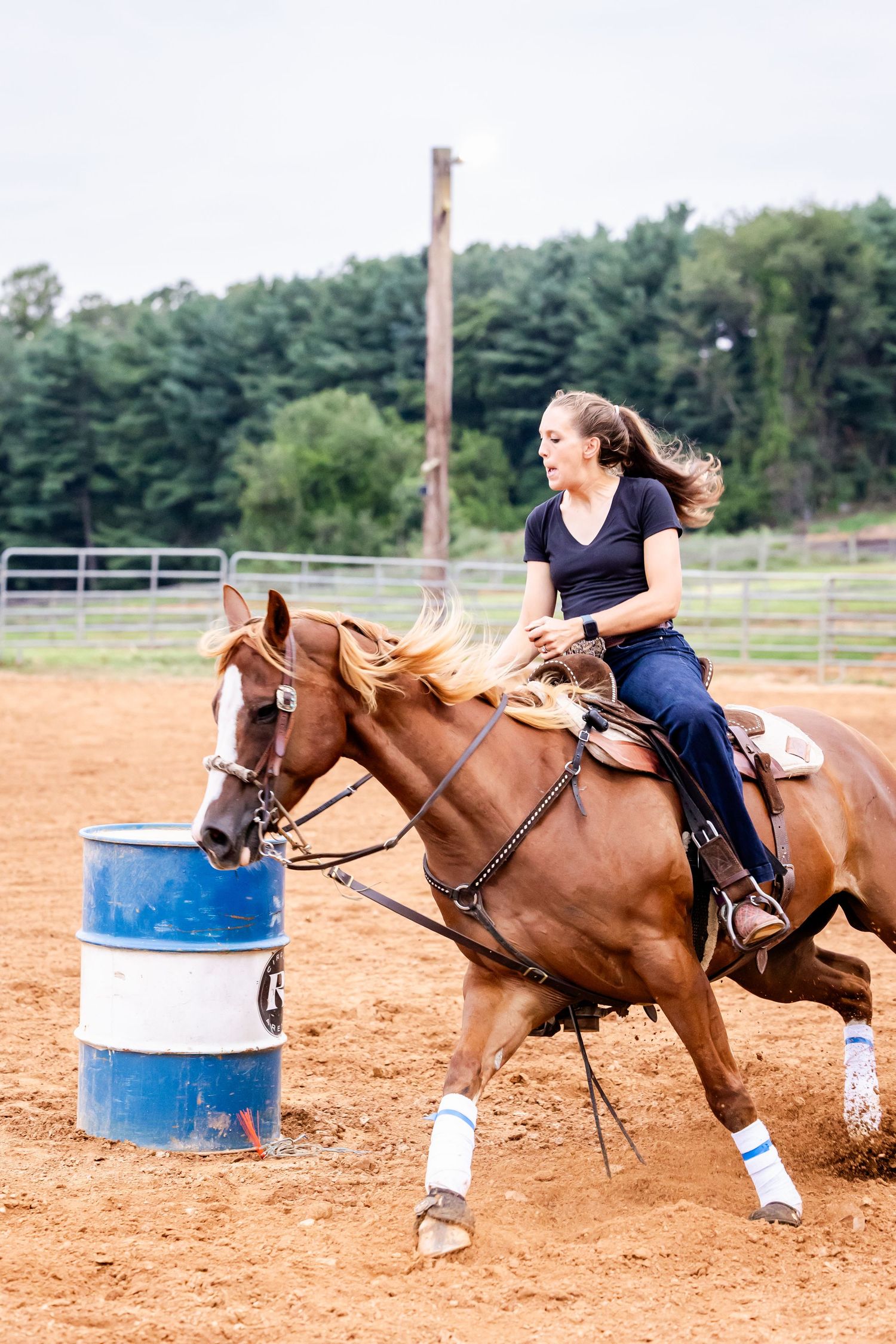 Horse and rider navigate around a blue barrel during a competitive barrel racing event.