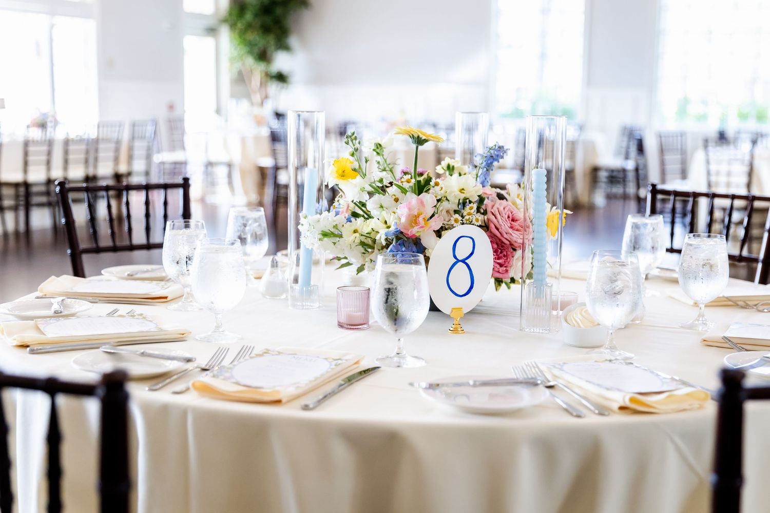 Elegant wedding reception table settings with white linens and floral centerpieces.