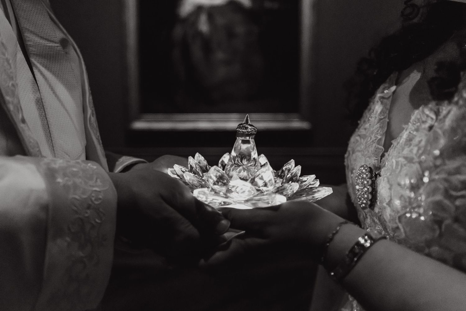 Black and white photo of delicate crown being held during wedding ceremony.