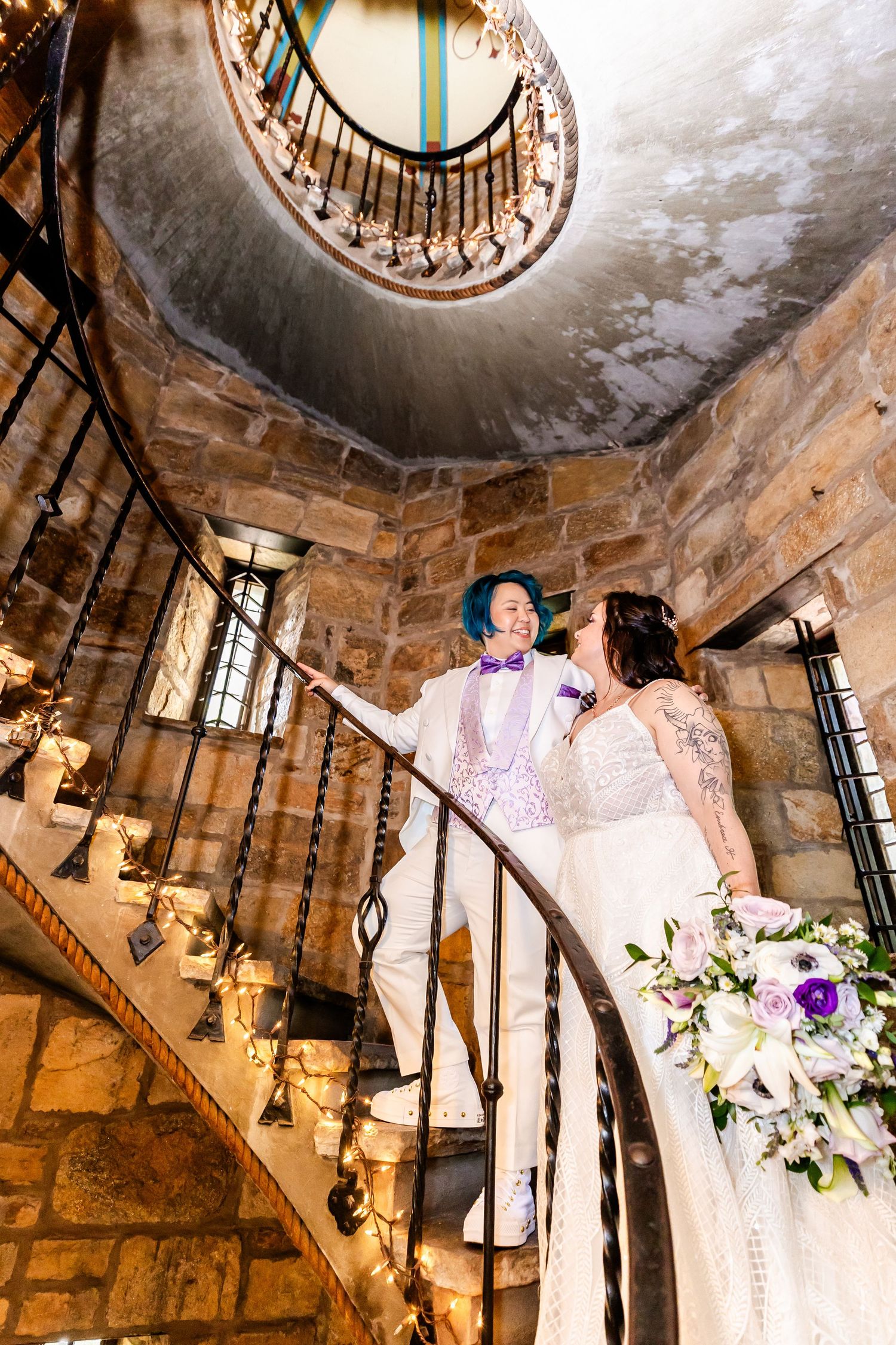 A romantic moment captured on a vintage spiral staircase in a stone castle setting.