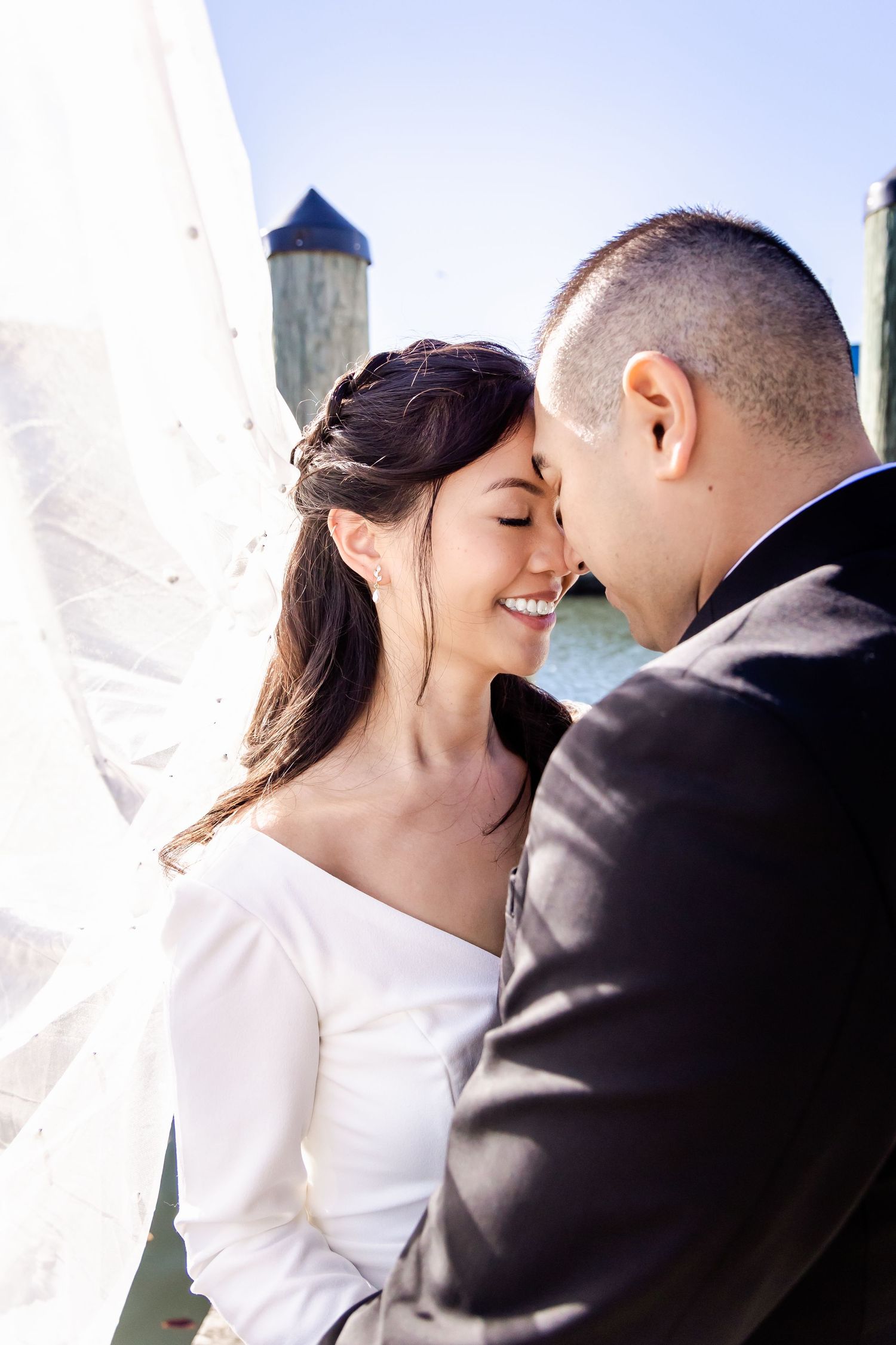 A romantic moment shared between newlyweds with a lighthouse in the background.