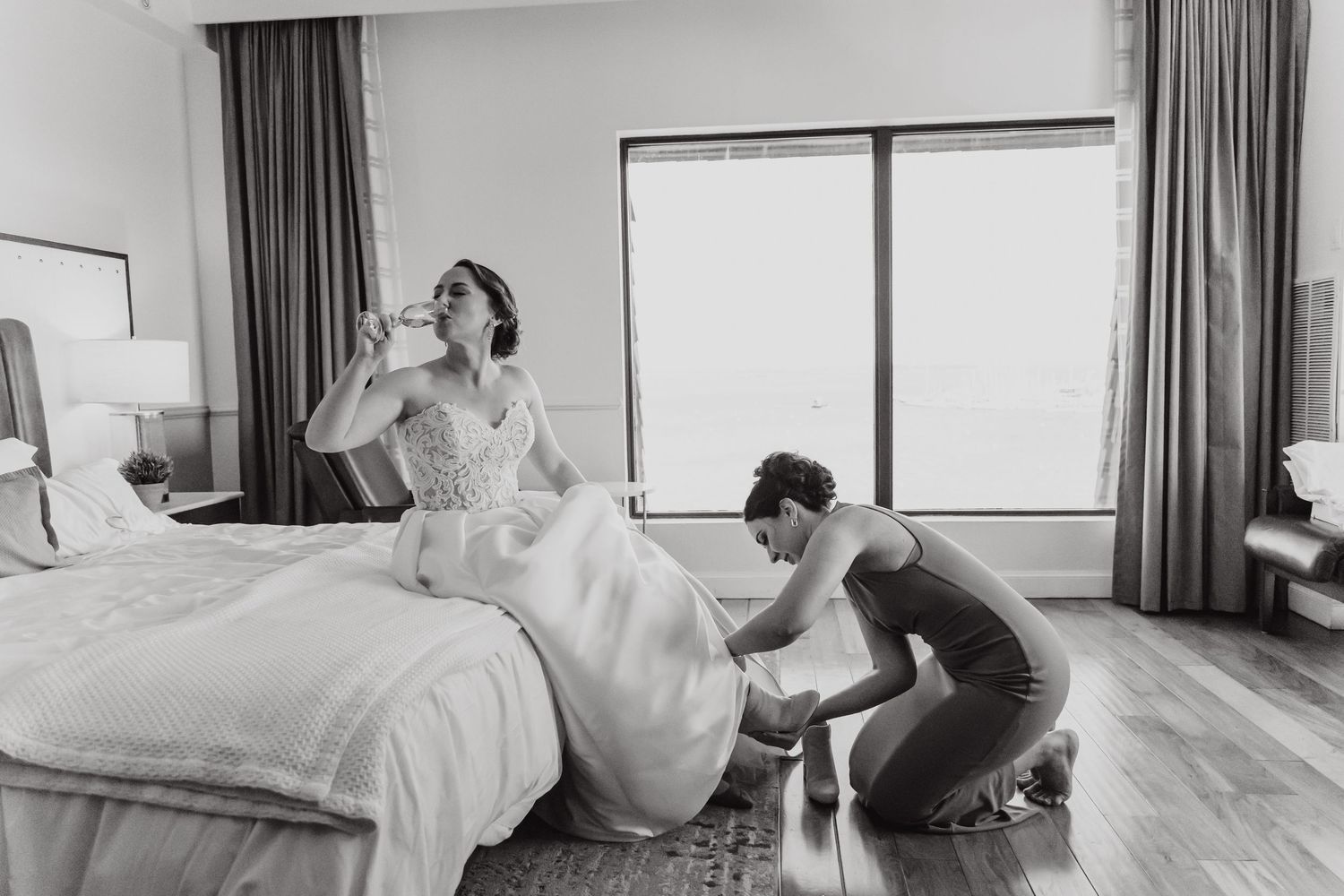 Four black and white photos show a person in a hotel room performing various poses on a bed.