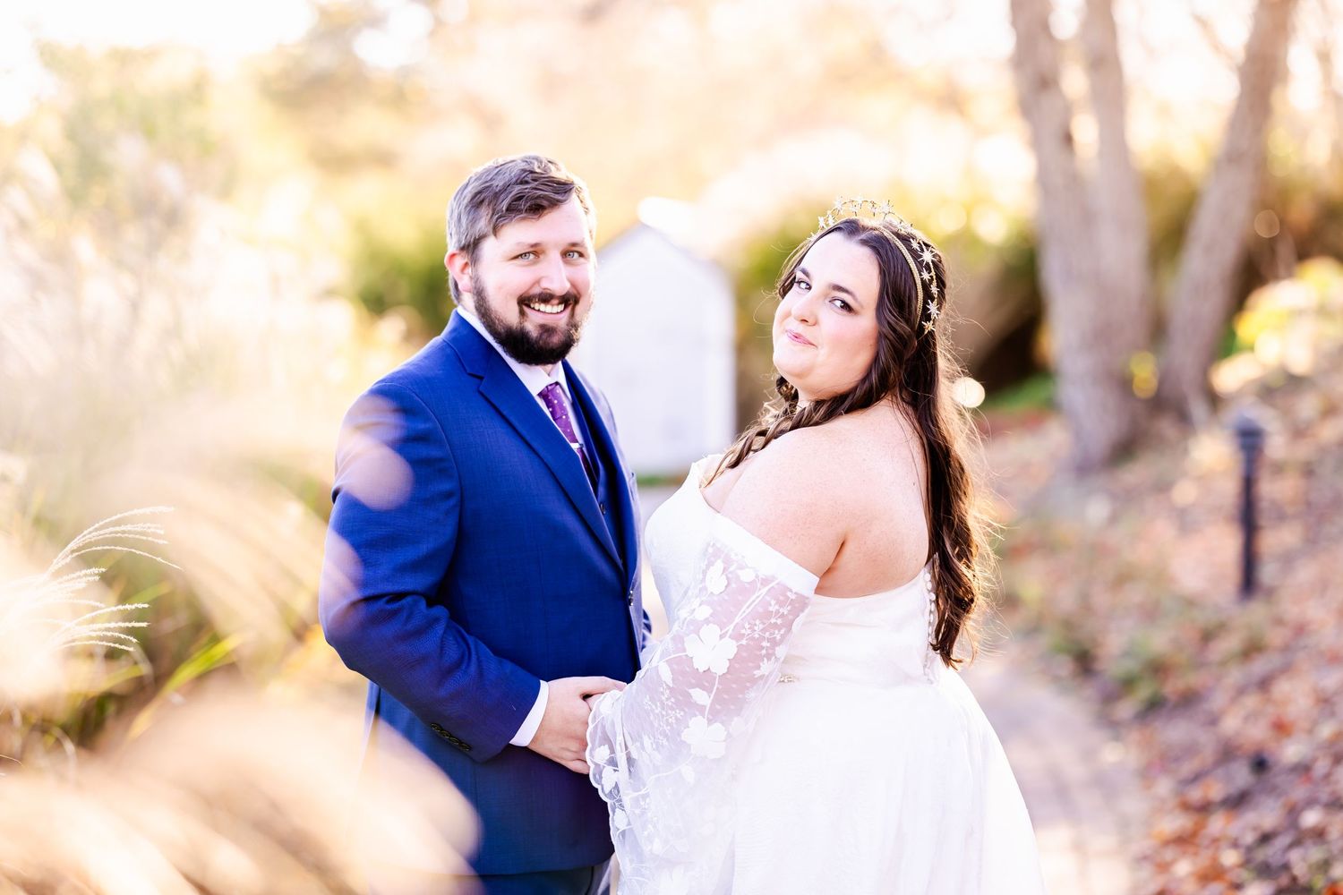 A newlywed couple shares a candid moment in a sun-lit outdoor setting.