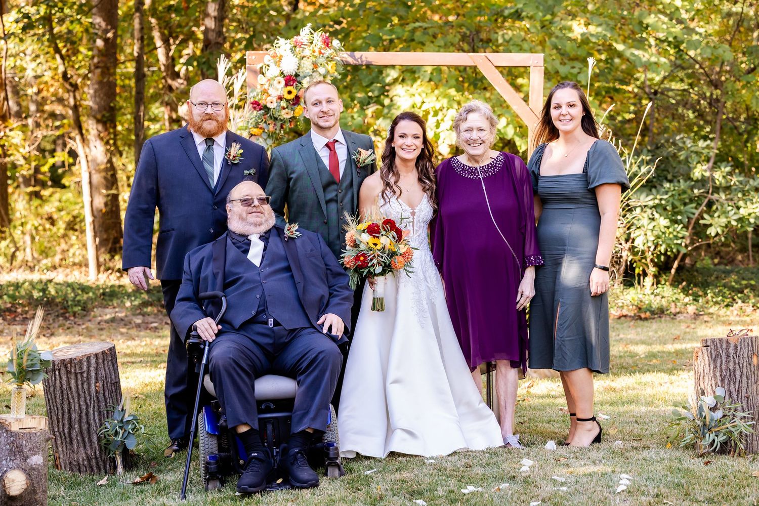 Group wedding photos being taken in a natural outdoor setting with purple and navy attire.