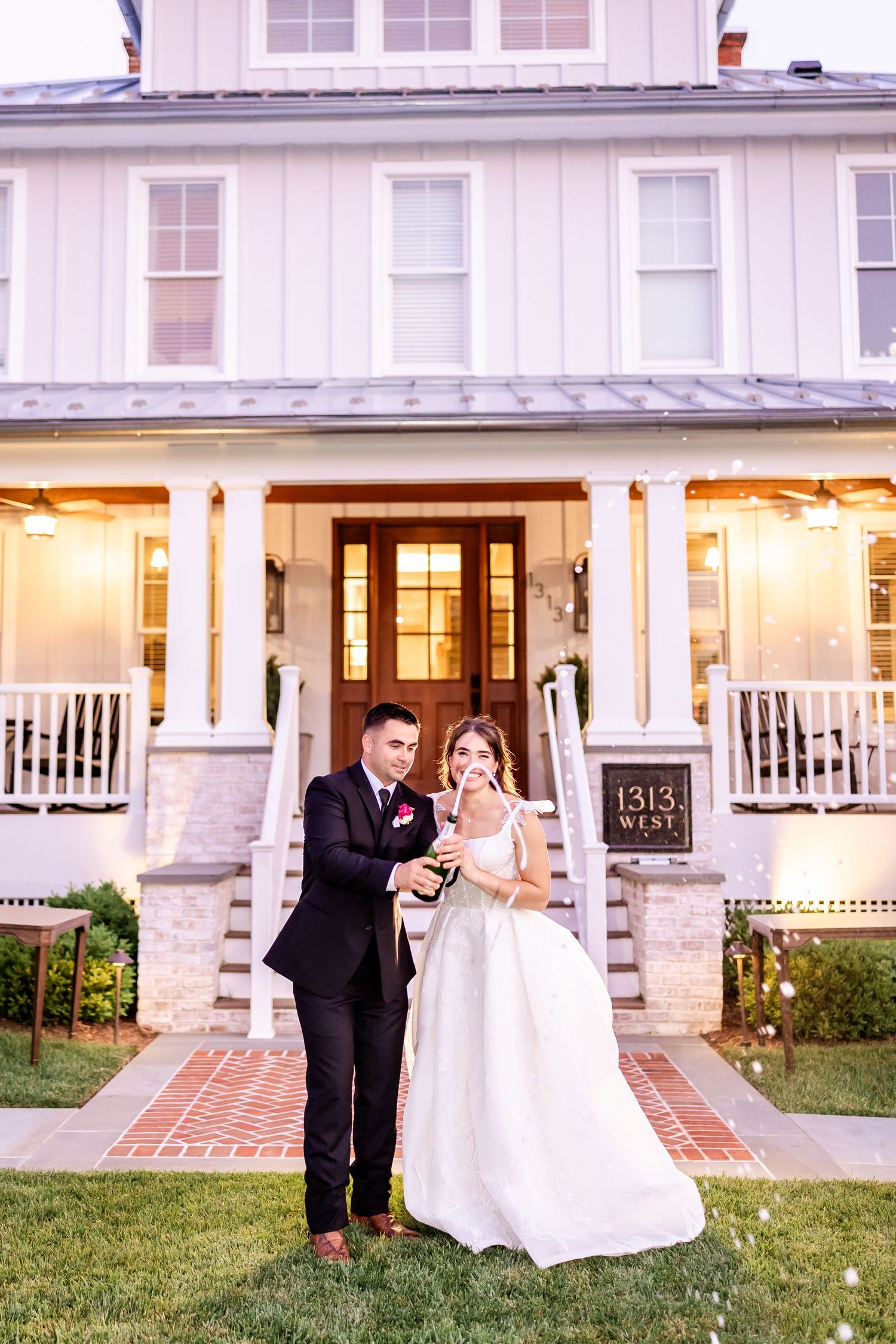 Wedding couple poses for romantic outdoor portraits at a classic white house with a wraparound porch.